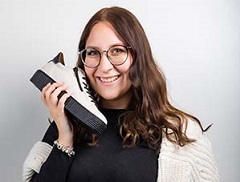 Mädchen hält sich weißen Sneaker wie einen Telefonhörer an die Wange